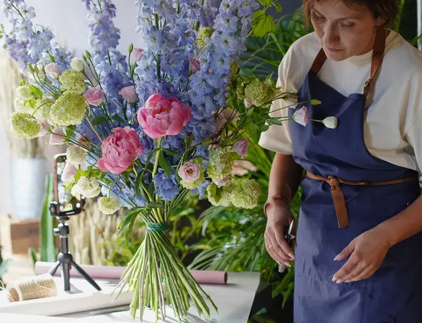 Çiçekçide bir çiçekçi mavi desenlerden bir buket yapar. Küçük bir iş. Yakın plan. Yumuşak odak.