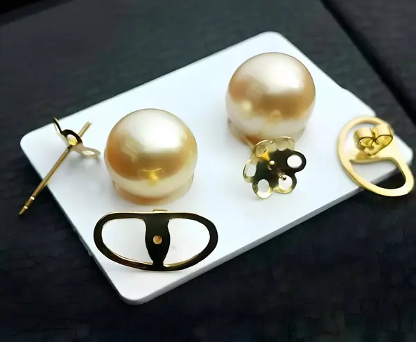 stock image A pair of large, golden South Sea pearl earrings with gold posts and backs. The pearls are smooth and lustrous, with a warm, golden hue.