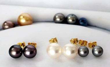 Three pairs of lustrous pearl stud earrings, showcasing variations in color and size, displayed on a neutral background. Gold posts add a touch of elegance. clipart