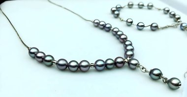 Zarif gri inci kolyeli, kolyeli ve uyumlu bir bileziği olan bir set. Herhangi bir kıyafete biraz incelik katmak için mükemmel..