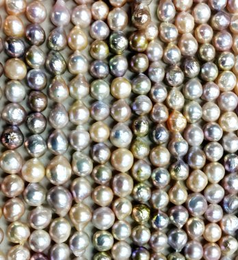 Yakın plan çekimde parlak keshi incileri sergileniyor. Pastel pembe, lavanta ve şampanya renkleri büyüleyici bir dizi sergileniyor. Düzensiz şekiller benzersiz karakter ekler.