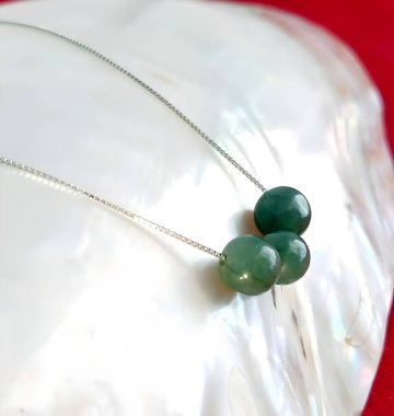 Parlak bir deniz kabuğunda duran yeşil yeşim taşlı narin bir kolye, el yapımı mücevherlerin zarafetini ve güzelliğini vurguluyor..