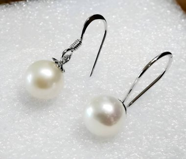 Yumuşak bir arka planda sergilenen güzel inci kancalı küpeler zarafet ve parlaklıklarını gözler önüne seriyor. Herhangi bir kıyafete lüks katmak için mükemmel..