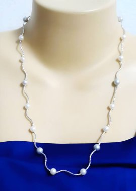 Bu zarif kolye inci ve boncuklu güzel bir tasarıma sahip, bir mankenin üzerinde sergileniyor, her kıyafete entelektüellik katmak için mükemmel..