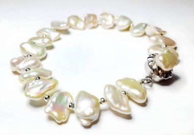 Bu zarif tatlı su inci bileziğin güzelliğini keşfedin. Benzersiz şekiller ve gümüş bir toka içeriyor. Her özel durum ya da günlük kıyafet için mükemmel.