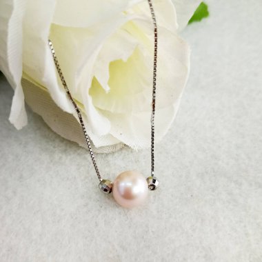 Güzel bir düzenleme, içinde beyaz bir gül bulunan teneke bardak pembe inci kolye, zarafet ve romantizmi simgeliyor, düğünler ya da özel durumlar için mükemmel..