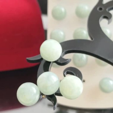 Dekoratif siyah bir stantta sergilenen zarif yeşim mücevherler.