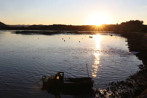 Santoa, Cantabria İspanya 'yı gökyüzünün sularında ve günbatımında bulutlarda kayık ve yansımalarla batırdı.