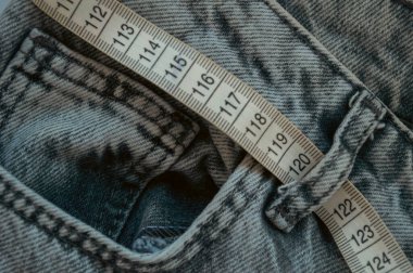 Beyaza izole edilmiş kot pantolon ile ölçüm bandı. Kilo verme konsepti. Yüksek kalite fotoğraf