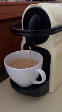 Bir fincan taze kahve demleyen kahve makinesi, beyaz bir fincana akan sıcak kahve, espresso yaparken yakalanır. Yüksek kalite 4k görüntü