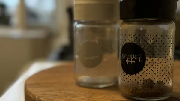 Şık cam baharat kavanozları. Parlak, modern bir mutfak ortamında, ahşap bir tahta üzerine yerleştirilmiş kapaklar.