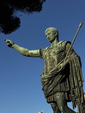 Detaylı bronz bir Roma imparatoru heykeli ufukta rahatça görünüyor. Canlı, mavi bir gökyüzü ile çevrelenmiş olan gökyüzü, ziyaretçilerin dikkatini tarihsel bir ortamda çeker..