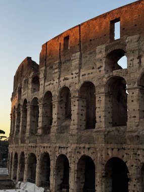 Altın ışık, günbatımında Roma 'da antik Kolezyum' u yıkıyor ve olağanüstü taş yapısını ve kemerlerini sergiliyor. Ziyaretçiler bu ikonik tarihi ve ihtişamı hayrete düşürüyor..