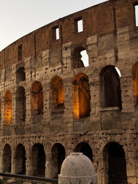 Roma 'nın görkemli kolezyumu, akşam yaklaşırken, alacakaranlık gökyüzüne karşı sıcak bir şekilde parlayan ve yüzyılların mimari dehasını gözler önüne seren ziyaretçiler tarafından takdir ediliyor..