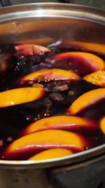 Kırmızı şarabın içinde portakal dilimleri ve paslanmaz çelik kapta baharatlar. şarap hazırlığı. Kış içeceği ve tatil yemekleri konsepti. Yüksek kalite 4k görüntü