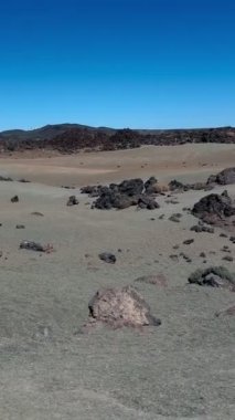 İspanya 'nın Tenerife kentindeki Teide Ulusal Parkı' nın kurak volkanik manzarası, dağınık kayaları ve derin mavi gökyüzünü gösteren gerçeküstü bir görüntüsü. - Evet. Yüksek kaliteli FullHD görüntüler