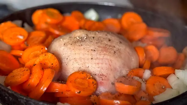 Taze havuç ve soğanla çevrili, tavada pişmiş et içeren lezzetli bir yemek..