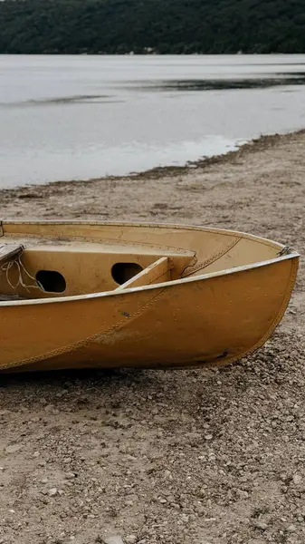 Kayalık bir göl kıyısındaki sarı bir tekneye yakın çekim.