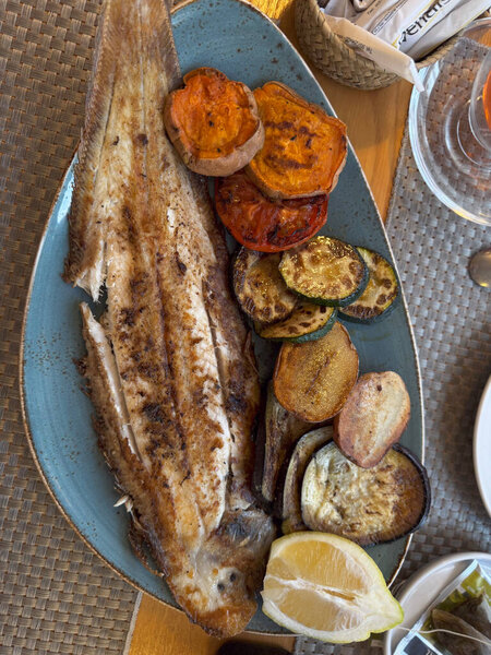 Gourmet Mediterranean seafood plate served with fresh vegetables, grilled to perfection in a fine dining restaurant in Ibiza.