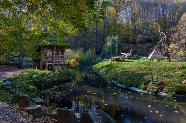 Hayvanat bahçesi manzarası, su seviyesi, ahşap binalar, Afrika köyü taklidi, sazlık çatılar, sonbahar güneşi, sarı yapraklar, sis.