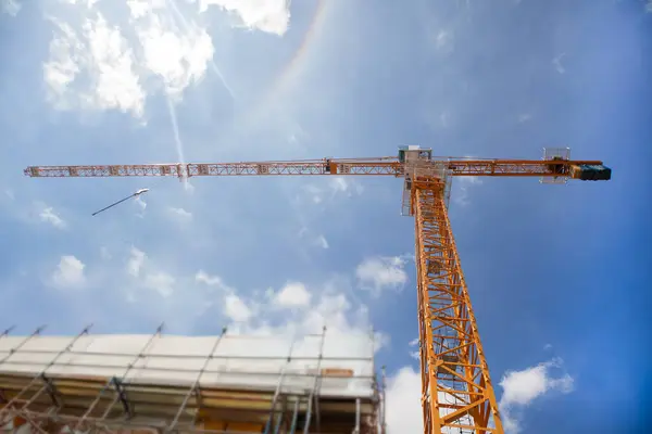 İnşaat alanındaki kule vinci öğle vakti güneş ışığı altında duruyor..