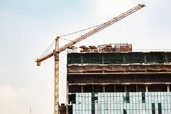 İnşaat alanındaki vinç ve mavi gökyüzü hakkında. Kule vincini vurguluyor.