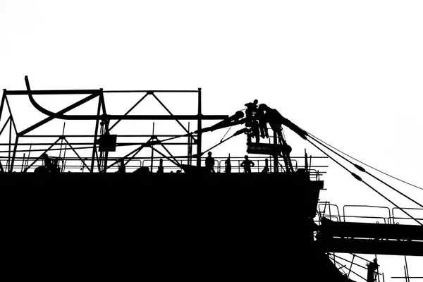 İnşaat alanında, kule vincini söken işçiler vardı ve başka bir vinç de gün batımında denize açılmak üzere hazır bekliyordu..