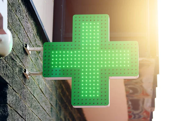 药店的招牌在建筑物上 药房绿灯横板 市中心的商店装饰 城市药房的标志 背景上的阳光 图库照片
