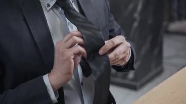 Kişi kravatını düzeltir. TV sunucusu veya gazeteci yayına çıkmaya hazırlanıyor. Takım elbiseli bir adam masada oturuyor. Haber kanalı.