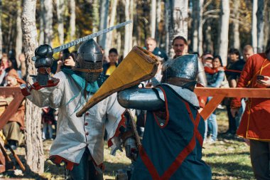 Ortaçağ mızrak dövüşü turnuvalarının yeniden inşası. Zırhlı ve miğferli şövalyeler, arenada kılıç ve kalkanlarla savaşıyorlar. Tarihi kulüpler festivali. Bishkek, Kırgızistan - 13 Ekim 2019