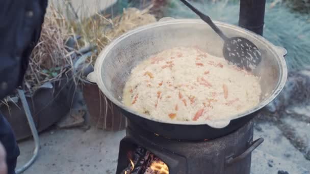 Hombre Mezcla Pilaf Kazan Con Cuchara Ranurada Cocinar Sobre Fogata — Vídeos de Stock