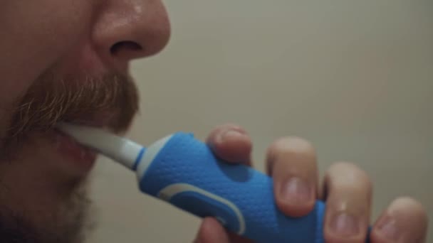 男は歯を電動歯ブラシで磨く 健康のための毎日のルーチン手順 男の顔に太い口ひげとひげ 口腔衛生 — ストック動画
