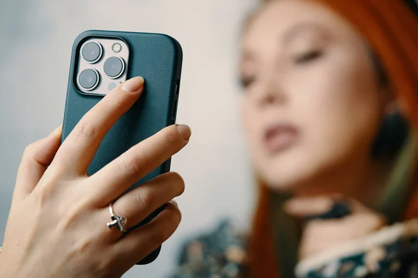 Moda kadını, iPhone 13 'te profosyonel selfie çekiyor. Üçlü lens kameralı Gadget. Her ihtimale karşı akıllı telefon tutan mantar yüzüklü kadınların yakın çekimi. Bishkek, Kırgızistan - 24 Ocak 2022