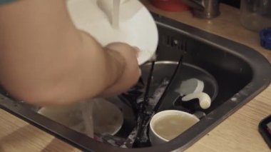İnsanların elleri sofra takımlarını yıkıyor. Aile yemeğinden sonra kirli bulaşıklarla dolu bir lavaboya yakın çekim. Ev işleri işte. Ev temizliği ve hijyen..