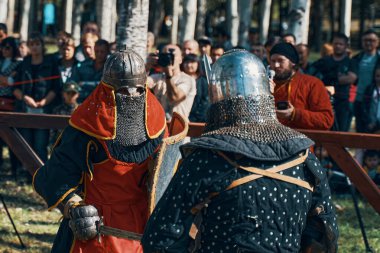 İki şövalye seyircilerin önünde arenada kavga ediyor. Zırhlı ve kılıçlı bir savaş. Ortaçağ mızrak dövüşü turnuvalarının taklidi. Bishkek, Kırgızistan - 13 Ekim 2019