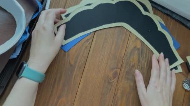 Dişilerin elleri tahta masaya etnik Slav tacı şeklinde bez ve plastik taban serer. Terzi ve işyeri. Eko-deri ve birbirine yapışkan dokuma kumaştan yapılmış..