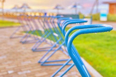 Bisiklet parkı okyanus kıyısındaki boş alanlar günbatımına ve plaj şemsiyelerine karşı