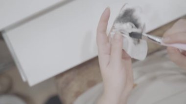 Kadınların elleri ıslak peçeteye siyah boya ile fırçayı siler. Sanatçılar iş akışı yapar. Pis paçavra. Üst görünüm.