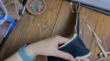 İğneci kadın dikişli üründeki fazla kumaşı kesiyor. Kadınların elinde makasın ve kumaşın en üst görüntüsü. Terzi, taç şeklinde etnik bir başlık yapar..