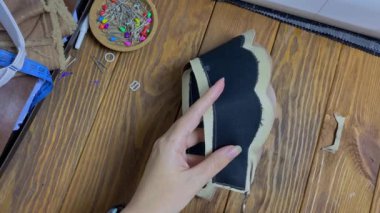 Terzi, taç şeklinde etnik bir başlık yapar. İğneci kadın dikişli üründeki fazla kumaşı kesiyor. Kadınların elinde düz bir makas ve kumaş ürünü..