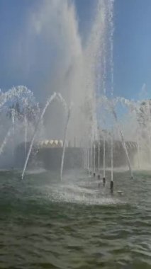 Güneşli bir günde muazzam bir yapının önünde muhteşem bir çeşme sergileniyor..