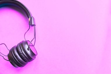 Düz konsept: Pastel pembe arka plan görünümlü siyah kulaklıklar.