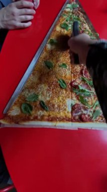 Taze sebzeler ve erimiş peynirle kaplı parlak kırmızı bir masada lezzetli bir dilim peynirli pizza.