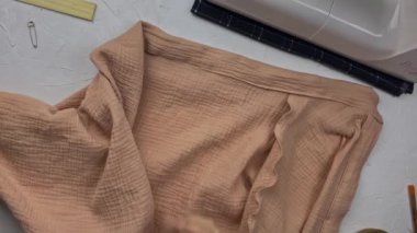 Kadınların elleri masanın üzerine hazır bir gömlek serer. Terzi, pamuk kılıfından elbiseler dikiyor. Yaratıcı bir insanın işyeri. Moda tasarımcısı.