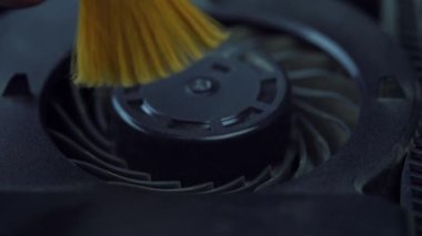 Elektronik cihaz konseptini yavaş çekimde onarıyor. İnsan eli kapatma, bakım veya profilaksi sırasında sarı fırçayla oyun konsolu veya dizüstü bilgisayarındaki tozu temizler. 
