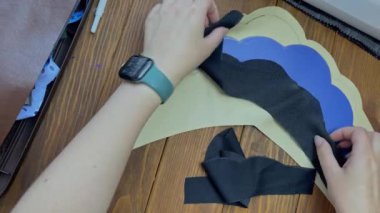 Kadınların elleri tahta masaya etnik Slav tacı şeklinde bez ve plastik taban serer. Eko-deri ve iç içe dokuma kumaştan yapılmış bir adres. Terzi ve işyeri.