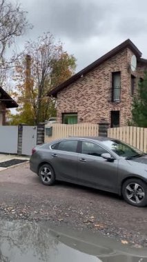 Zarif, şık ve modern bir ev. Etrafı canlı bir sonbahar yeşilliği ve yakınlarda park edilmiş bir araba ile çevrili.