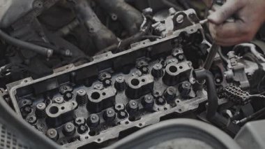 Otomobil tamirhanesinde çalışan bir tamircinin elleri motor bileşenlerine odaklanıyor..