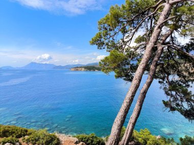 Phaselis kıyısındaki dağların ve kayaların panoramik manzarası güneşli havada Kemer yakınlarındaki Akdeniz 'in mavi ve berrak suyuyla. Antalya, Türkiye.