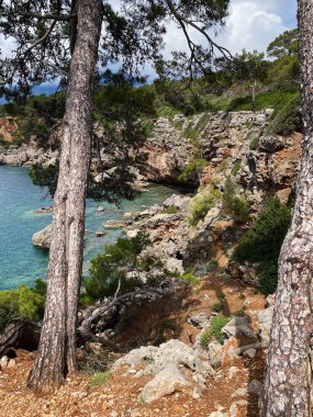 Güneşli bir havada, Akdeniz 'in mavi ve berrak sularıyla Phaselis kıyısındaki dağların ve kayaların manzarası. Antalya, Türkiye.